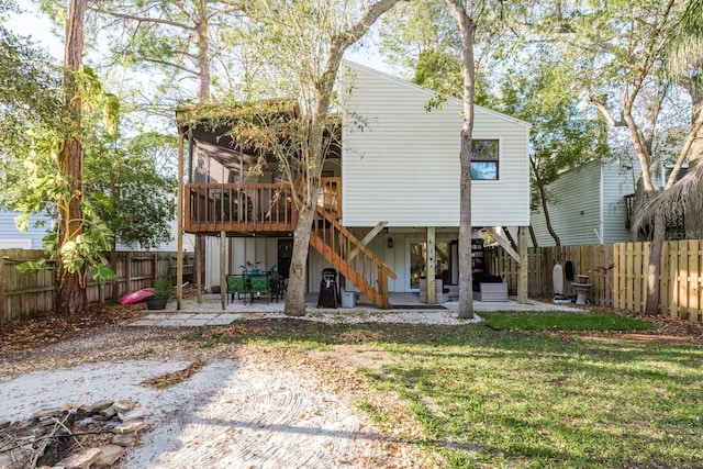 rear view of house with stairway, a patio area, a lawn, and a fenced backyard