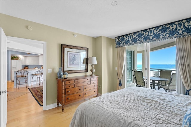 bedroom featuring baseboards, light wood-style flooring, and access to outside