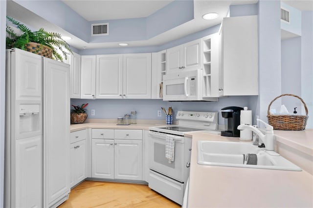 kitchen with white cabinetry, white appliances, visible vents, and a sink