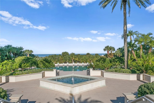 view of pool with a water view, an in ground hot tub, and a patio