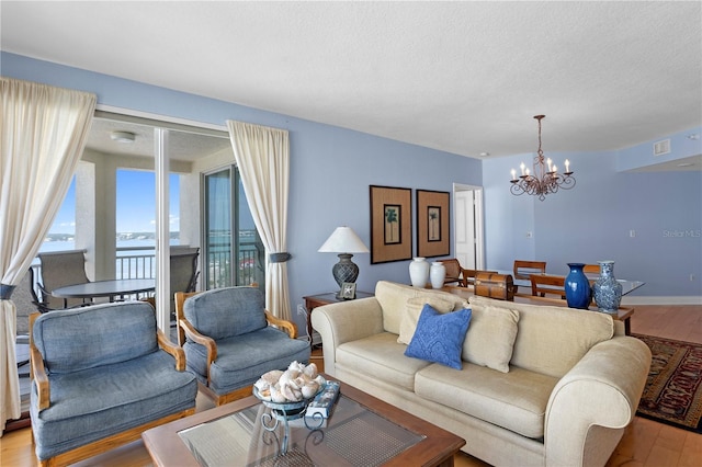 living room with a chandelier, light wood-type flooring, visible vents, and a water view