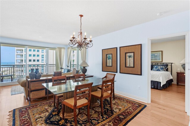 dining area featuring light wood finished floors, a notable chandelier, and baseboards