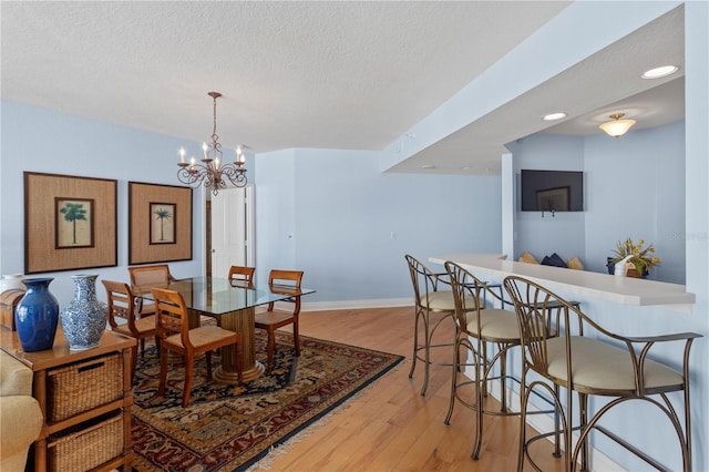 dining room featuring a textured ceiling, baseboards, recessed lighting, wood finished floors, and a notable chandelier
