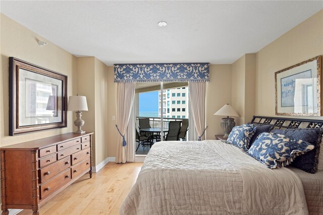 bedroom with light wood finished floors, access to outside, and baseboards