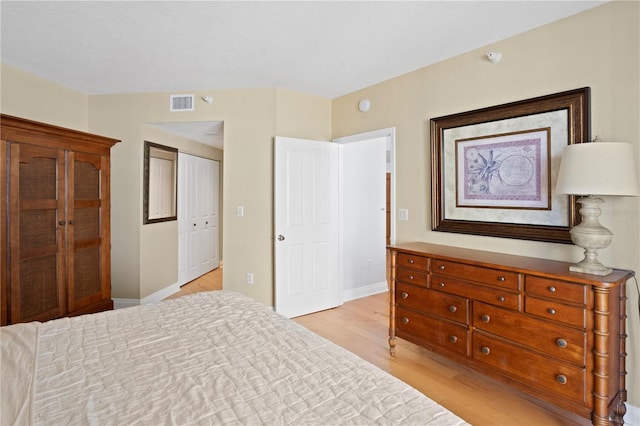 bedroom with a closet, visible vents, baseboards, and light wood-style floors