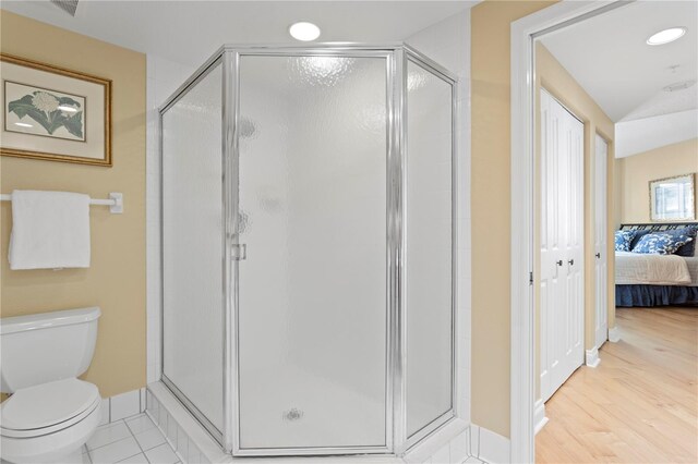 full bathroom featuring toilet, a shower stall, and ensuite bath
