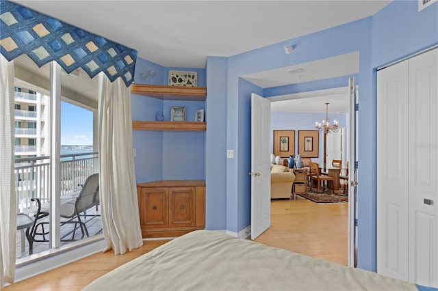 bedroom featuring access to outside, an inviting chandelier, a closet, and light wood-style flooring