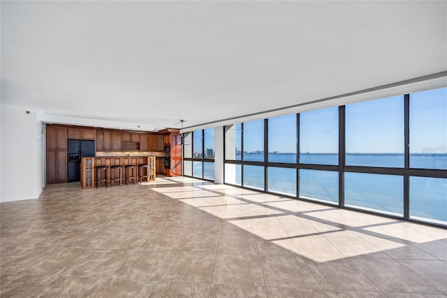 unfurnished living room with expansive windows, a water view, and bar area