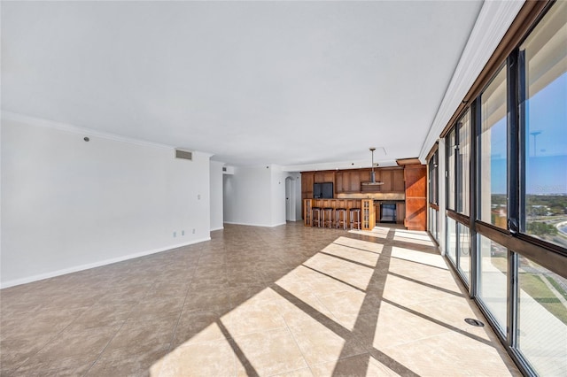 unfurnished living room featuring visible vents, crown molding, and baseboards