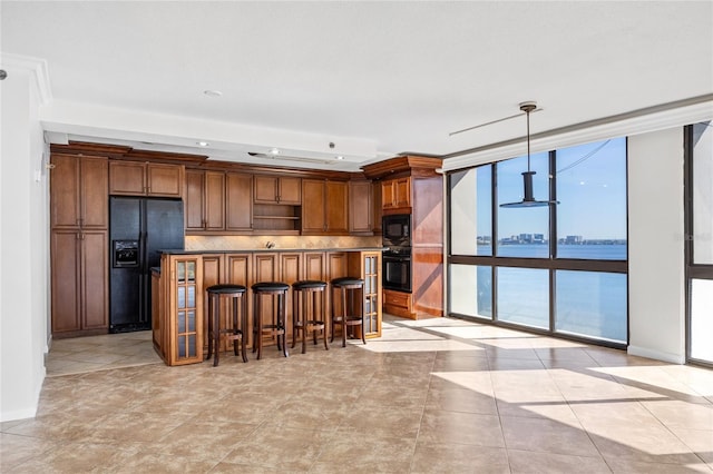 kitchen featuring a breakfast bar area, black appliances, expansive windows, decorative light fixtures, and backsplash