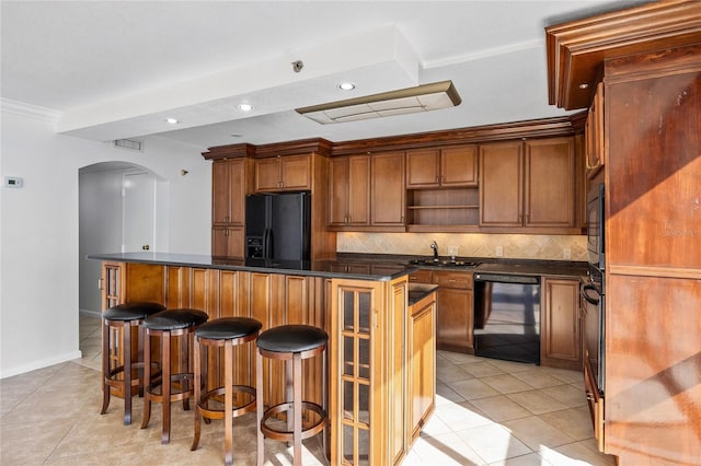 kitchen featuring dark countertops, backsplash, arched walkways, black appliances, and open shelves