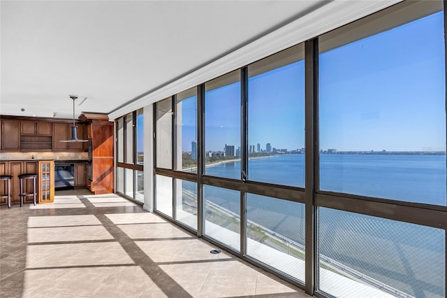 unfurnished sunroom with a city view and a water view