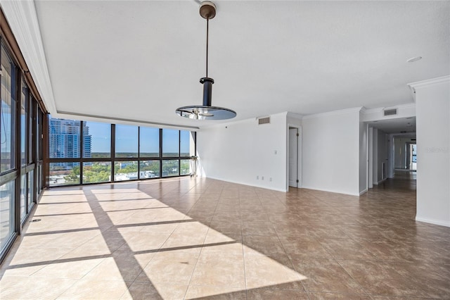 spare room featuring expansive windows, visible vents, baseboards, and ornamental molding