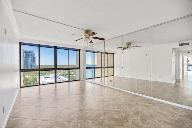 spare room with tile patterned floors, visible vents, ornamental molding, floor to ceiling windows, and ceiling fan