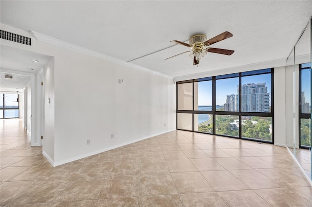 spare room featuring visible vents, a wall of windows, baseboards, and ornamental molding