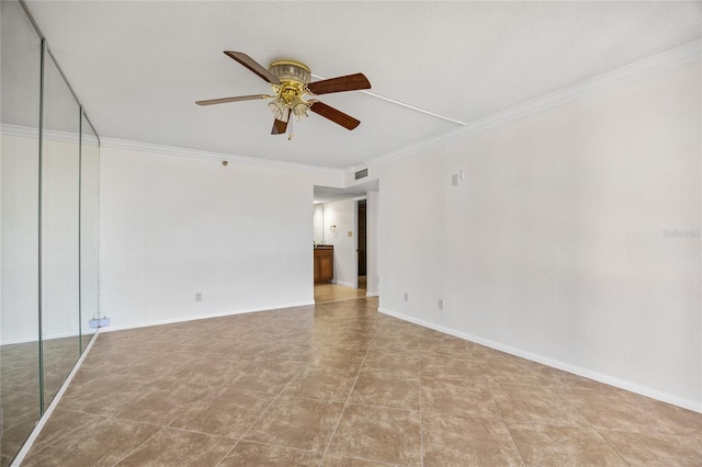 empty room with ornamental molding, visible vents, baseboards, and ceiling fan