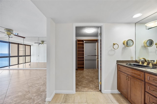 full bathroom featuring tile patterned floors, a walk in closet, ceiling fan, and vanity