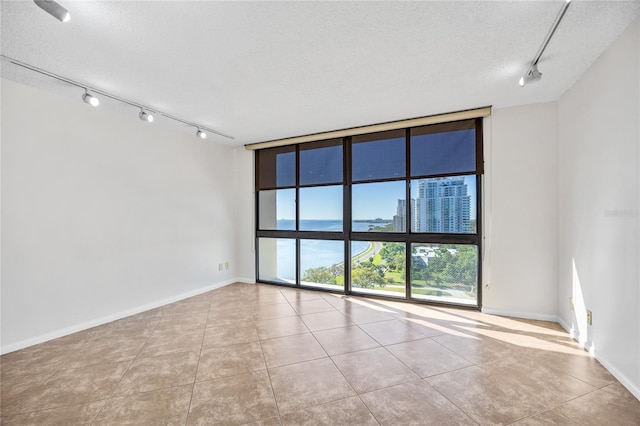 empty room featuring a textured ceiling, a city view, baseboards, and expansive windows