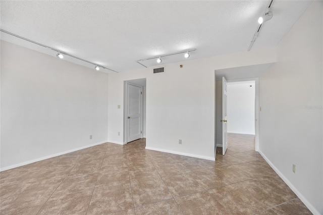 unfurnished room featuring visible vents, a textured ceiling, rail lighting, and tile patterned flooring