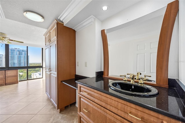 bathroom with tile patterned floors, a ceiling fan, expansive windows, a textured ceiling, and vanity