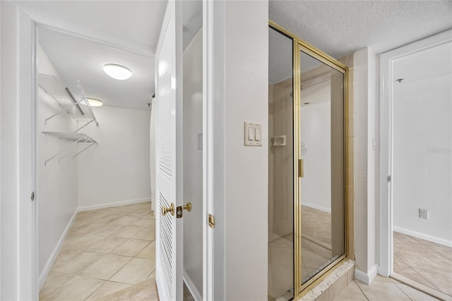 bathroom featuring tile patterned floors, a stall shower, a textured ceiling, and baseboards