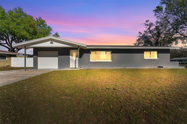 ranch-style house with a lawn, an attached garage, driveway, and fence