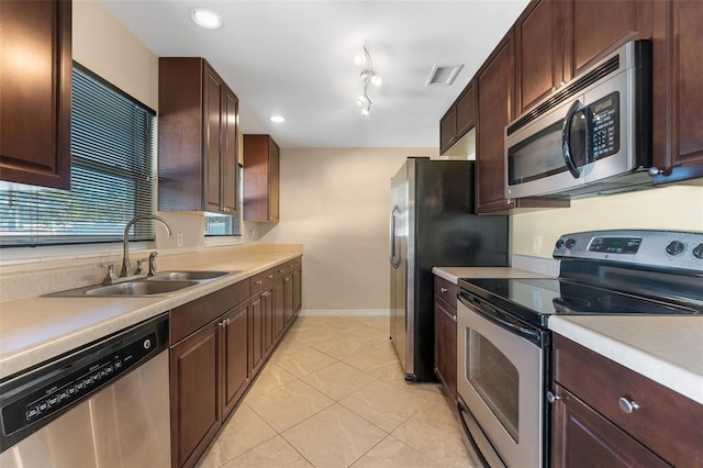 kitchen with dark brown cabinets, appliances with stainless steel finishes, light countertops, and a sink