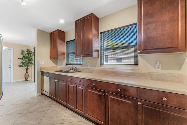 kitchen featuring baseboards, light countertops, light tile patterned floors, stainless steel dishwasher, and a sink