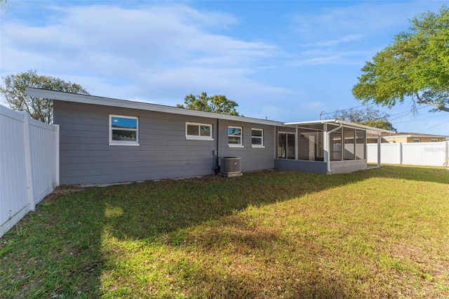 rear view of property featuring a lawn, cooling unit, a fenced backyard, and a sunroom