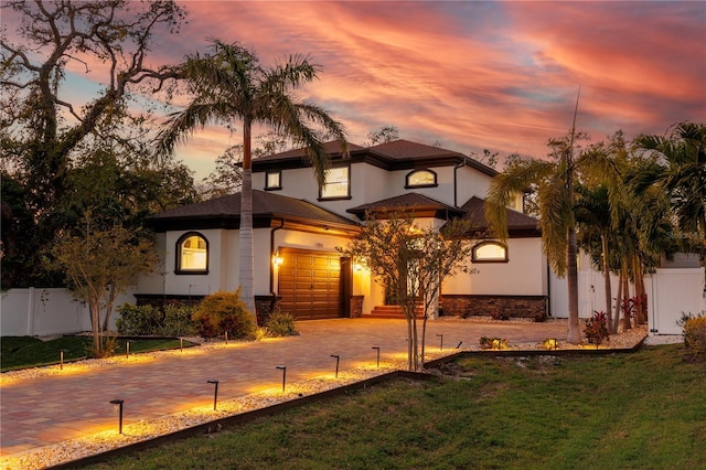 view of front facade featuring stucco siding, driveway, a front lawn, and fence