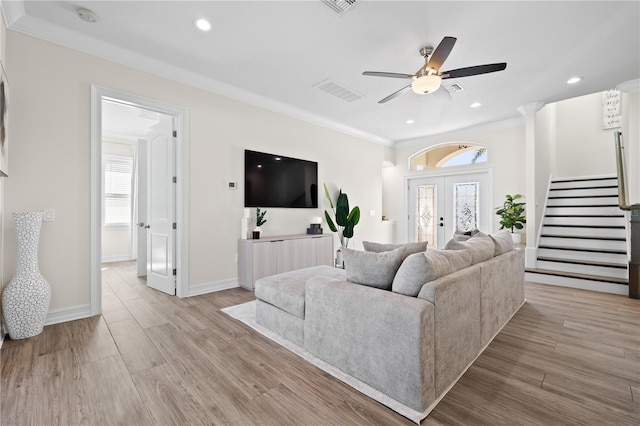 living area with stairs, wood finished floors, french doors, and ornamental molding