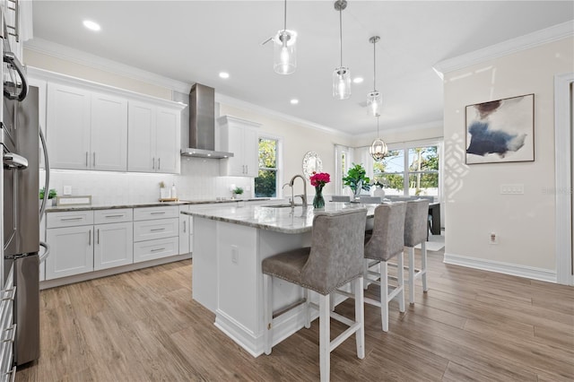 kitchen featuring ornamental molding, wall chimney exhaust hood, tasteful backsplash, and a sink