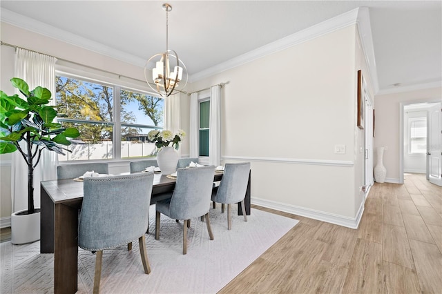 dining area featuring light wood finished floors, baseboards, crown molding, and an inviting chandelier