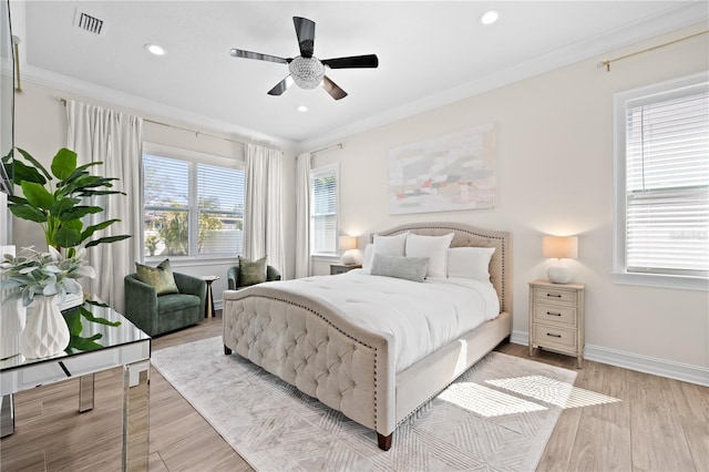 bedroom with visible vents, baseboards, wood finished floors, and crown molding