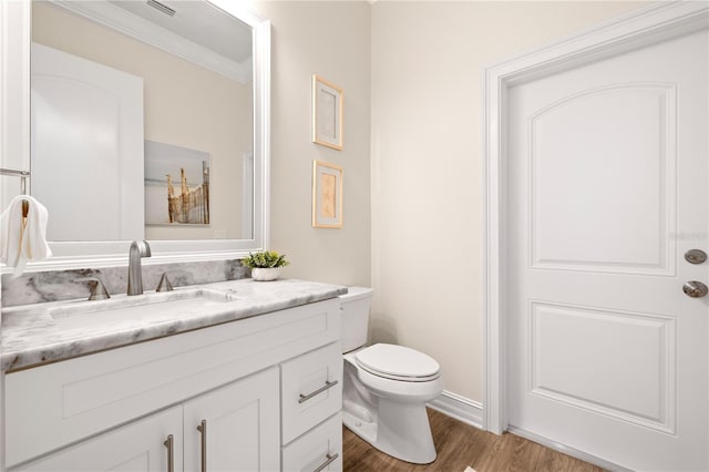 bathroom featuring vanity, wood finished floors, visible vents, ornamental molding, and toilet