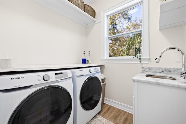 washroom featuring light wood-type flooring, washer and clothes dryer, a sink, baseboards, and laundry area