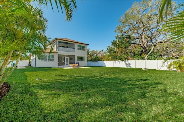 view of yard featuring a patio, a balcony, and a fenced backyard