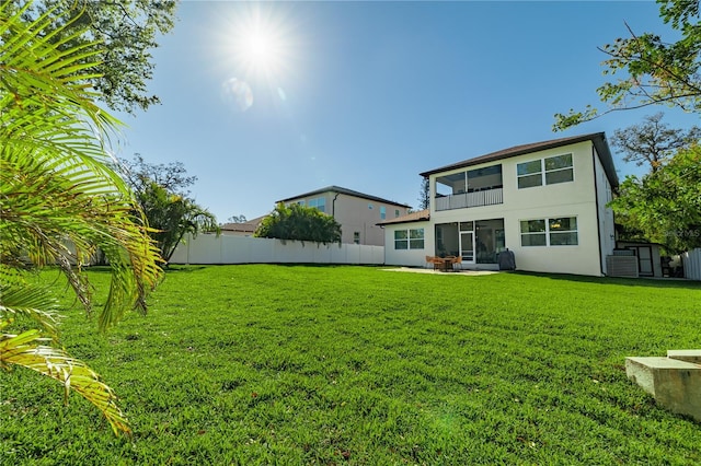 rear view of house with a patio, a fenced backyard, a lawn, and stucco siding