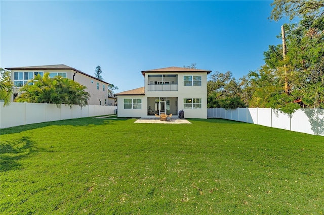 back of house featuring a yard, a fenced backyard, stucco siding, and a patio area