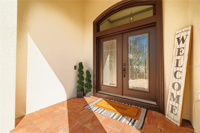 view of exterior entry with french doors and stucco siding