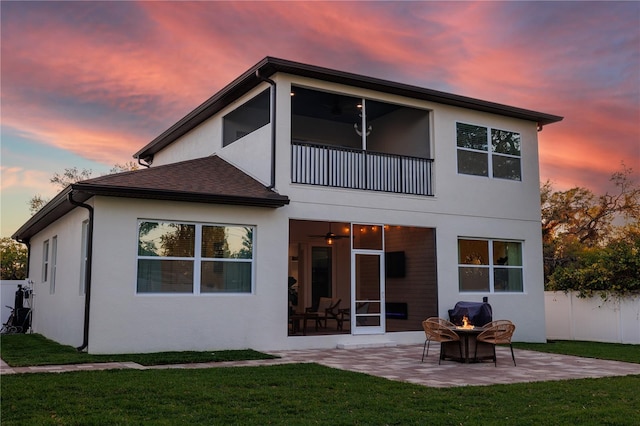 rear view of house with fence, stucco siding, a yard, a sunroom, and a patio