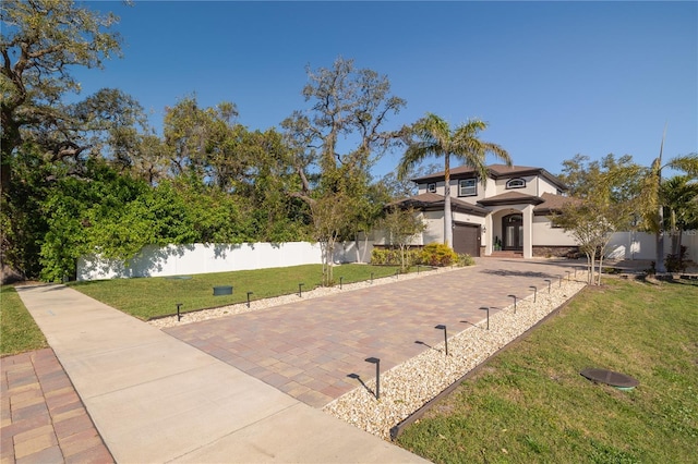 mediterranean / spanish-style house featuring a garage, stucco siding, a front yard, and fence