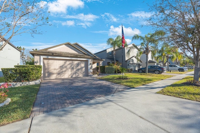 view of front facade featuring decorative driveway, an attached garage, a front yard, and stucco siding