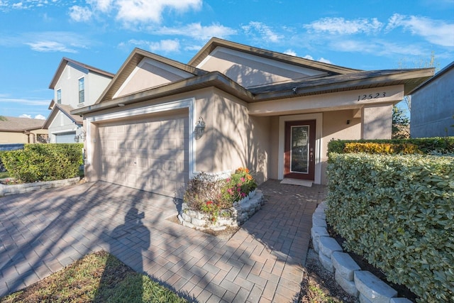 ranch-style home featuring stucco siding, an attached garage, and driveway