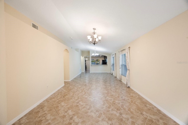 empty room featuring arched walkways, visible vents, baseboards, and an inviting chandelier