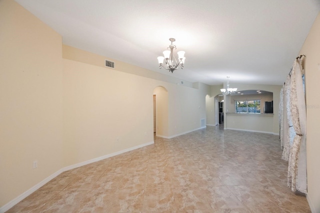 spare room with visible vents, baseboards, lofted ceiling, arched walkways, and a notable chandelier