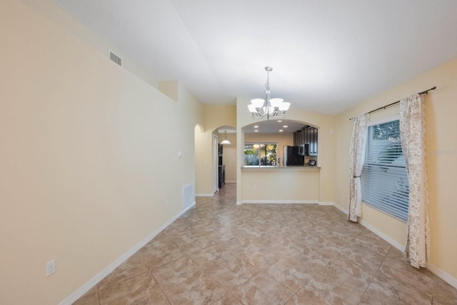 unfurnished dining area featuring an inviting chandelier, visible vents, arched walkways, and baseboards