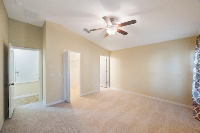 unfurnished bedroom with visible vents, baseboards, light colored carpet, a spacious closet, and vaulted ceiling