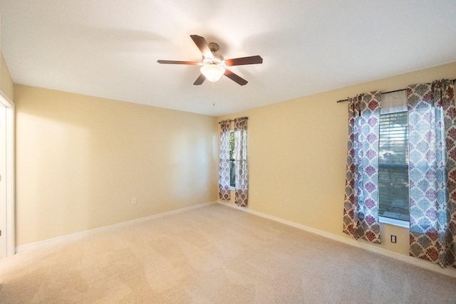 empty room featuring ceiling fan, baseboards, and light carpet