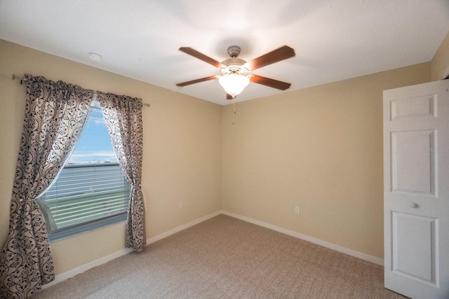 carpeted empty room featuring baseboards and ceiling fan